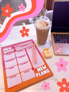 a laptop computer sitting on top of a table next to a pink and orange planner