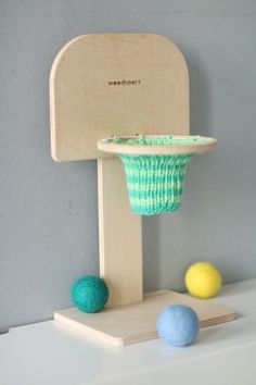 a wooden toy with three balls in front of it and a chair on the other side