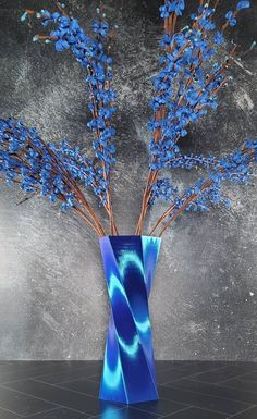 a blue vase filled with flowers on top of a black countertop next to a gray wall