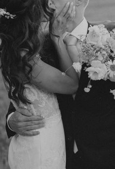 black and white photograph of bride and groom kissing each other with flowers in their hair