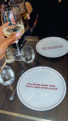 people are sitting at a table with wine glasses and plates on it that say, you never know who you'll meet over a slice