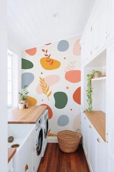 a washer and dryer in a small room with colorful wallpaper on the walls