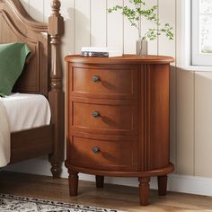 a bedroom scene with focus on the nightstand and bed in the foreground, along with a plant