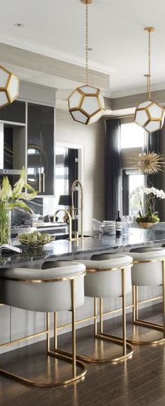 an elegant kitchen with gold accents and marble counter tops, along with white stools