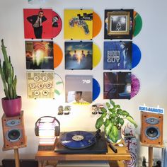 there is a record player on the table in front of many records and plants,