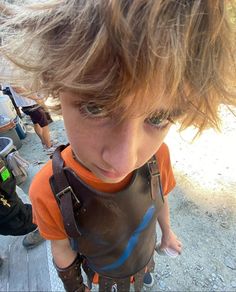 a young boy wearing a brown leather vest and orange shirt