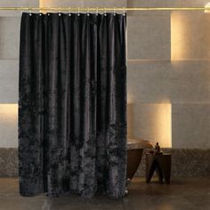 a black shower curtain in a bathroom next to a bathtub and toilet with lights on the wall