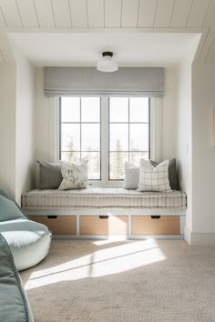 a window seat in the corner of a room with two pillows on top of it