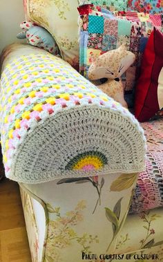 a crocheted blanket on top of a bed next to pillows and stuffed animals