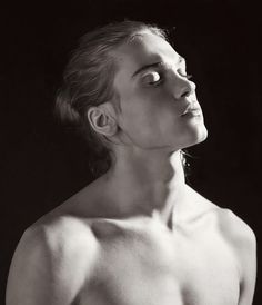 a black and white photo of a shirtless man looking up at something in the air