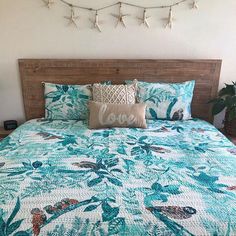 a bed with blue and green bedspread in a bedroom next to a potted plant