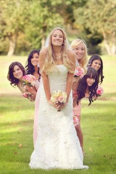 a group of women standing next to each other on top of a lush green field