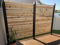 a wooden fence next to a house with a potted plant