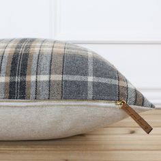 a plaid pillow on a wooden floor with a tag hanging from it's side