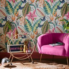 a pink chair sitting in front of a colorful wallpaper