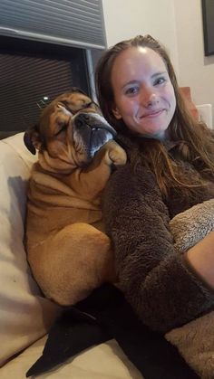 a woman sitting on top of a couch holding a dog