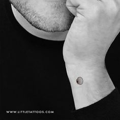 a man with a small seashell tattoo on his left wrist and right hand under his chin