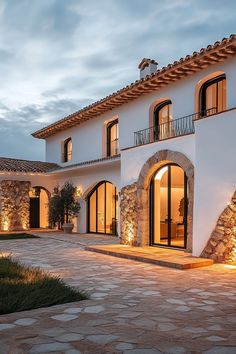 a large white house with lots of windows and lights on the side of it at night