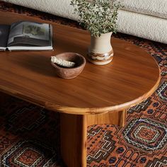 a wooden table with a book and bowl on it in front of a white couch