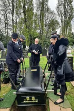 some people are standing near a grave and looking at something on the ground in front of them