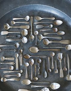 an assortment of spoons and forks arranged in a circle on a black plate with silverware