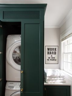 a washer and dryer in a room with green cabinetry, white walls and windows