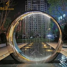 a fountain that is sitting in the middle of a park at night with lights on it