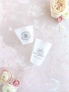 three paper cups sitting on top of a table next to flowers and confetti