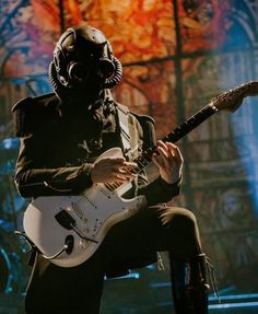 a man in a gas mask playing an electric guitar