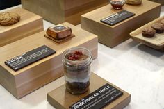 there are many different desserts on display in the glass jars and wooden trays