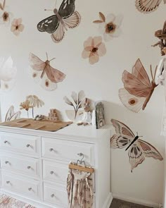 a baby's room with butterflies on the wall and dressers in front of it