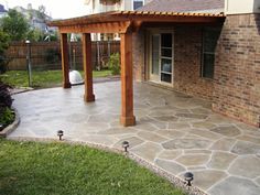 an outdoor patio with stone walkway and pergolated area