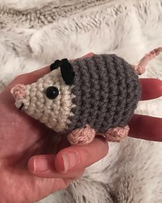 a hand holding a small crocheted toy mouse in it's left hand