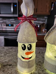 two lighted bottles with faces on them sitting on a counter