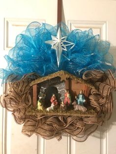 a nativity scene hanging on the front door with blue tulle and star above it