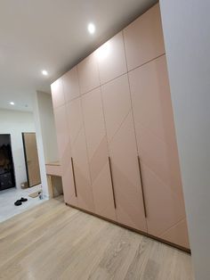 an empty room with wooden flooring and pink cupboards on the wall next to it