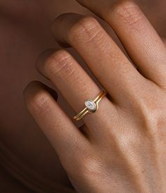 a woman's hand wearing a gold ring with a diamond on the middle finger