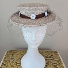 Brand: College Miss Hats  Size: 23 (see measurements) Color: ecru/brown/cream  Fabric Content: straw/tulle/ plastic    Features: You couldn't help but have a good time in this hat. Monochromatic color scheme with a chocolate brown grosgrain ribbon hat band, ecru hat and white buttons around the band. Sweet and fun. The netting is in great condition.    Measurements: Crown Circumference: 18in  Height: 2in  Brim:2 ½ in Strap Length:   Condition: Very good vintage condition. This hat was decommissioned from a museum's collection and has been well-preserved.   Care: spot clean only  Vintage sizing varies. Please check your measurements thoroughly and ask any questions before your purchase. No returns or exchanges. Condition is noted in the product description and can be observed using the zoom Fitted Retro Cream Hat, Retro Fitted Cream Hat, Retro Cream Hat, Cream Straw Hat With Short Brim, Vintage Beige Visor Hat, Retro Cream Hat With Curved Brim, Vintage Beige Top Hat With Curved Brim, Vintage Beige Top Hat With Short Brim, Vintage Fitted Cream Top Hat