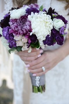 a bride holding a bouquet of purple and white flowers