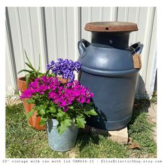 purple flowers are in pots next to a large gray container