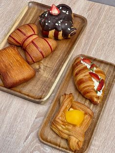 two wooden trays filled with pastries and croissants on top of a table