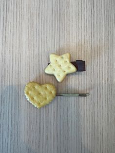 two cookies shaped like stars on top of a wooden table next to a toothpick