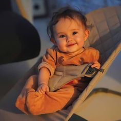 a baby sitting in a chair smiling at the camera