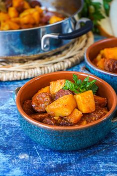 two bowls filled with food sitting on top of a blue tablecloth next to a metal pan