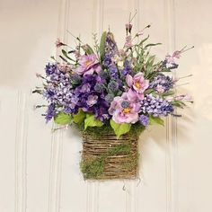 a basket filled with purple flowers sitting on top of a white door sill next to a wall