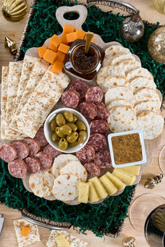 a platter filled with meats, cheese and crackers next to other snacks