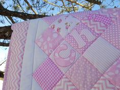 a pink and white quilt hanging from a tree