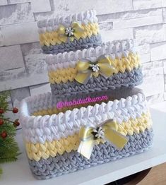 three crocheted baskets with bows on them sitting on a table next to a christmas tree