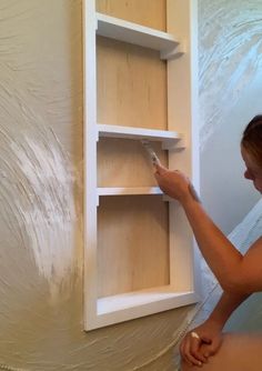 a woman is painting the wall with white paint