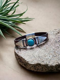 This leather bracelet is a bestseller and a must-have for any boho-chic wardrobe. Handmade with genuine leather, the bracelet features a striking turquoise stone in the center, surrounded by Southwest-inspired designs. The cuff style allows for a comfortable fit, making it a versatile accessory that can be dressed up or down. The unique indie style of this bracelet makes it a standout piece of jewelry that is sure to turn heads. Whether you're looking to add some bohemian flair to your outfit or Bohemian Brown Leather Bracelet, Bohemian Leather Strap Bracelets For Festivals, Adjustable Bohemian Cuff Bracelet With Leather Strap, Adjustable Leather Strap Bohemian Cuff Bracelet, Bohemian Leather Bracelet For Festivals, Southwestern Style Turquoise Leather Bracelet For Festivals, Adjustable Bohemian Jewelry With Leather Strap, Bohemian Turquoise Leather Cuff Bracelet, Rustic Turquoise Leather Bracelet